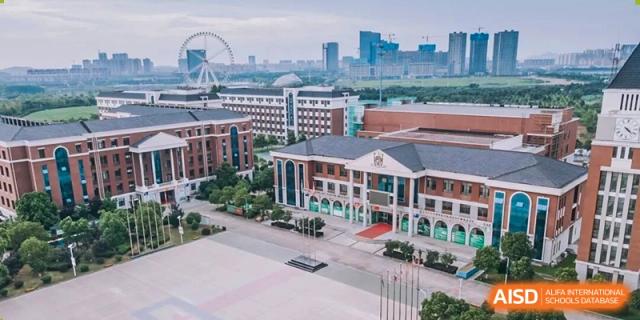 An aerial view of the school campus buildings with a modern city skyline in the background at Maple Leaf International School-Zhenjiang.