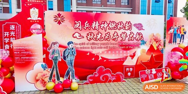 A colorful stage backdrop with Chinese text and a graphic of a figure, likely for an event or celebration, at Maple Leaf International School-Zhenjiang.