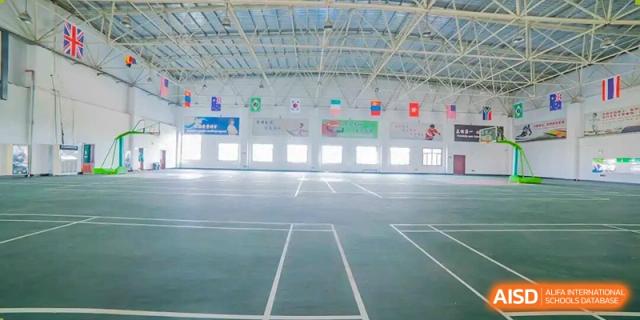 The spacious, empty floor of a large indoor gymnasium or sports hall at Maple Leaf International School-Zhenjiang.