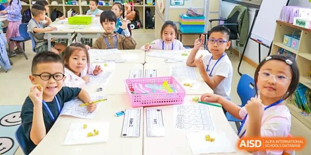 Young students seated at tables working on a hands-on learning activity in a classroom at Shanghai High School International Division.