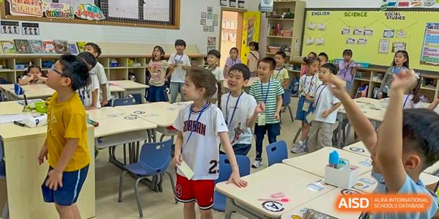 Young students smiling and moving around during a classroom activity at Shanghai High School International Division.