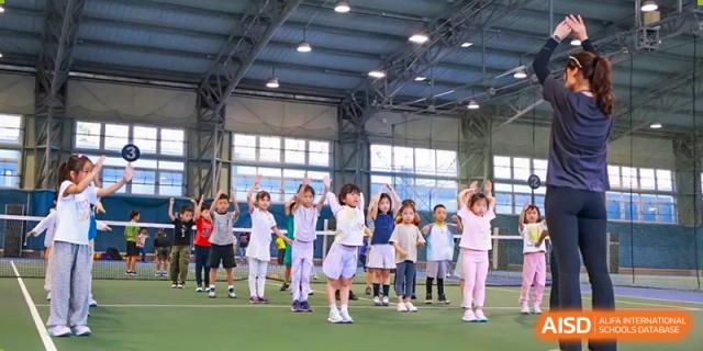 A group of young students performing a synchronized routine outdoors under a covered sports area at Shanghai High School International Division.