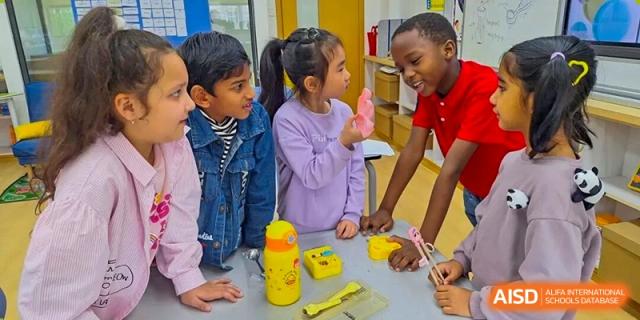 A diverse group of young Wenzhou Union International School (WUIS) students seated together and collaborating on a hands-on building project using yellow blocks.