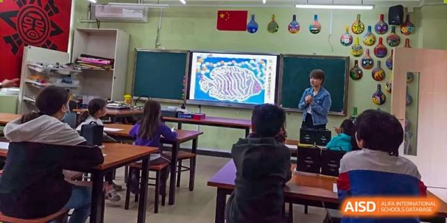 A Wenzhou Union International School (WUIS) student seated in a classroom, looking at a large screen displaying a scientific diagram of the brain.