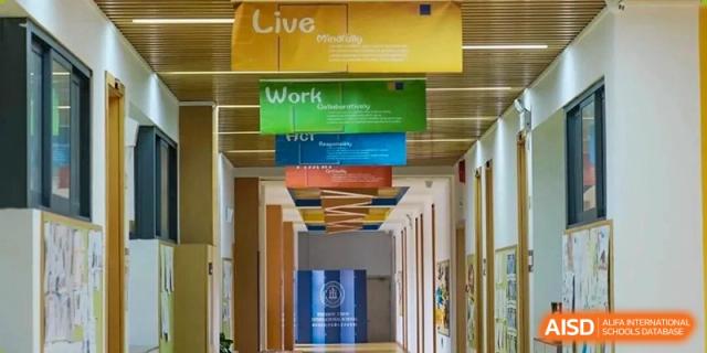 A view of a bright, modern hallway at Wenzhou Union International School (WUIS) with motivational banners, including the words "Live" and "Work," hanging from the ceiling.