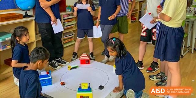 Wenzhou Union International School (WUIS) students working together on a robotics or science project on a white table.