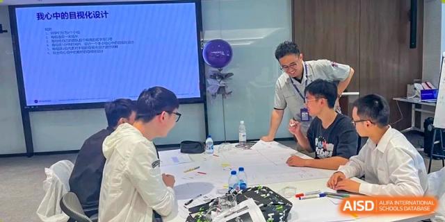 A teacher leaning over a table to discuss a design or engineering blueprint with a student at Wuxi No.1 High School.