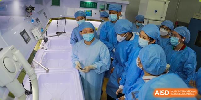 A group of students and an instructor, all dressed in surgical scrubs, participating in a hands-on medical or pre-med training session at Wuxi No.1 High School.