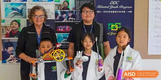 A young student holding an educational robot or scientific model at a school event at Yang Guang Qing International School of Beijing.