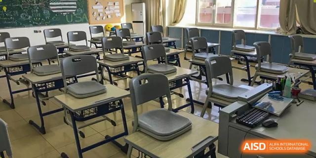 An empty classroom featuring rows of modern desks and chairs at Yang Guang Qing International School of Beijing.