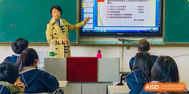 A close-up of a teacher pointing to content on a large interactive smart board in a classroom at Yang Guang Qing International School of Beijing.
