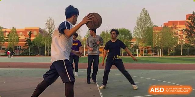 Students playing basketball on an outdoor court at Yang Guang Qing International School of Beijing.