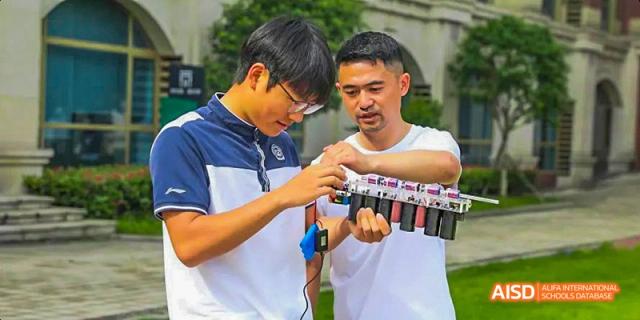 A male student and an adult collaborator working together to assemble or test a complex robotic or electronic device outdoors, at 21ST Century School, Wenjiang, Chengdu.