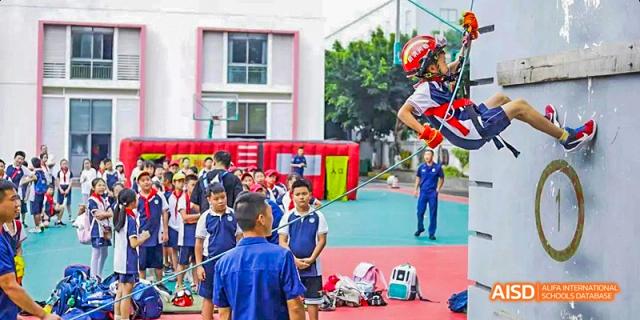 Students and teachers on a school playground, with a student wearing a red helmet preparing to jump, at 21ST Century School, Wenjiang, Chengdu.
