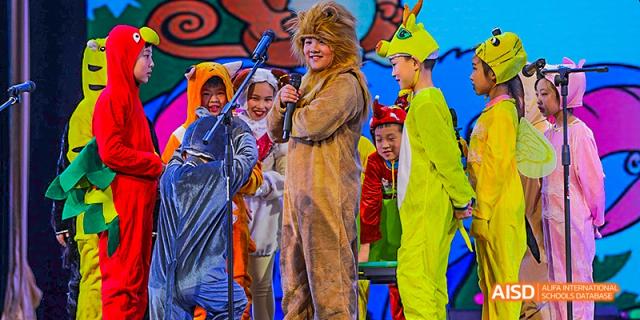 Students dressed in vibrant costumes, including one in a full-body animal suit, performing on an outdoor stage for an audience, at 21ST Century School, Wenjiang, Chengdu.