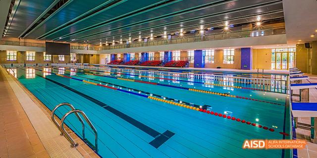 A view of the multi-lane indoor swimming pool facility with clear blue water and spectator seating, at 21ST Century School, Wenjiang, Chengdu.