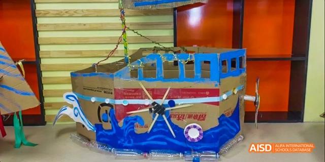 An elaborate student-built model, possibly a ship with a clock, constructed from painted cardboard at BDA School of The High School Affiliated to Renmin University of China.