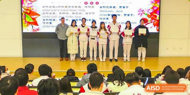 A line of students standing on a stage holding certificates or awards during a school event or ceremony at BDA School of The High School Affiliated to Renmin University of China.