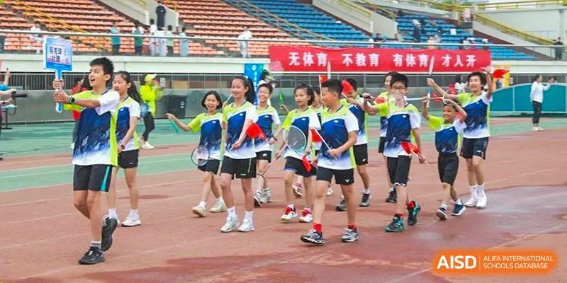 Students in green shirts cheering while holding small flags or props during a sports event at BDA School of The High School Affiliated to Renmin University of China.
