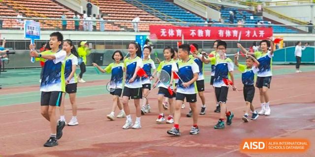 Students in green shirts cheering while holding small flags or props during a sports event at BDA School of The High School Affiliated to Renmin University of China.