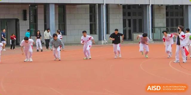 Students in white and red uniforms running on an outdoor track during a sports practice or race at BDA School of The High School Affiliated to Renmin University of China.