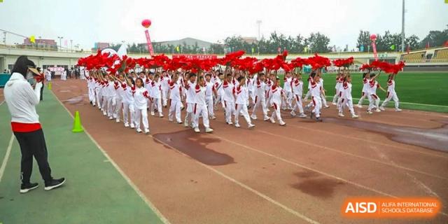 A large group of students in red and white running in formation on an outdoor track at BDA School of The High School Affiliated to Renmin University of China.