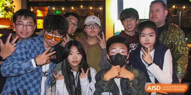 A group of students from BDA School of The High School Affiliated to Renmin University of China posing for a picture at an event, with some giving peace signs and one wearing a mask.
