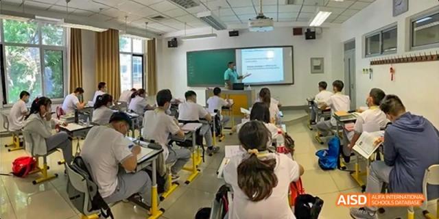A wide view of a classroom at Beijing No.2 Middle School where students are seated while a teacher instructs at the front, using a large screen display.