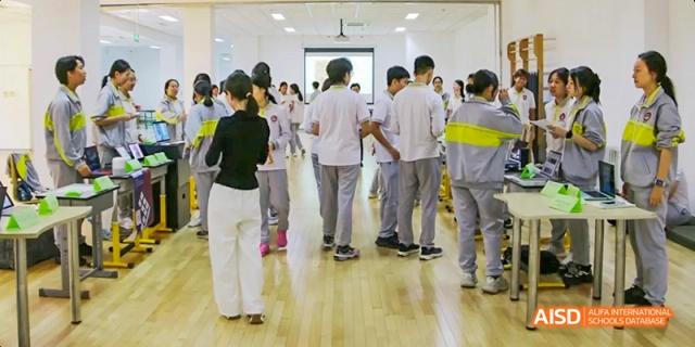 Students from Beijing No.2 Middle School are gathered in a group in a hallway or large room, listening to a teacher or instructor.