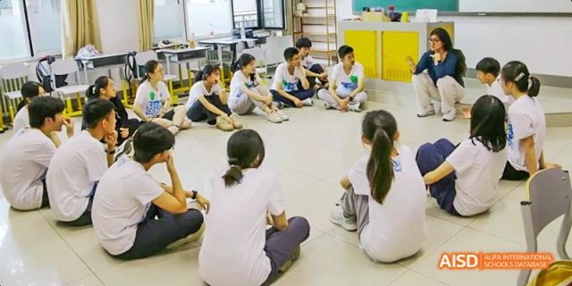 A group of students from Beijing No.2 Middle School sitting on the floor in a circle, engaged in a collaborative activity or discussion.