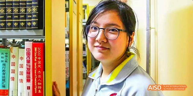 A close-up portrait of a female student from Beijing No.2 Middle School wearing glasses and a light uniform shirt.