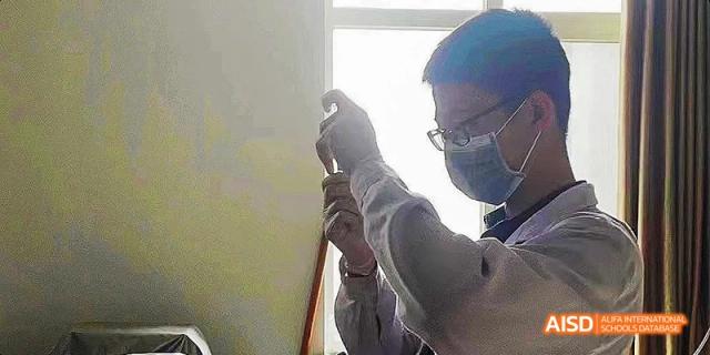 A student from Beijing No.2 Middle School working with scientific equipment, holding a test tube or pipette in a lab setting.