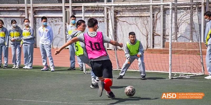 An action shot of students from Beijing No.2 Middle School playing soccer/football, with one player dribbling the ball while another attempts a tackle.