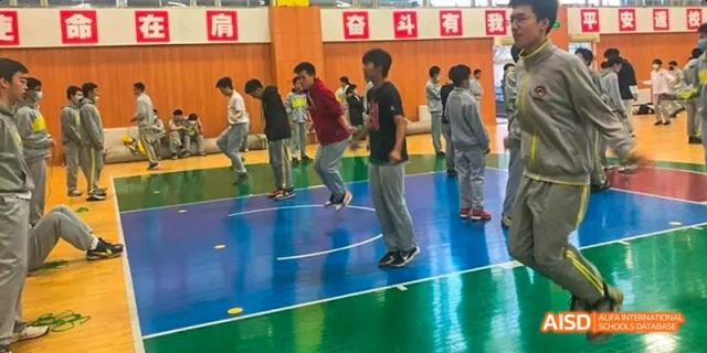 Students from Beijing No.2 Middle School participating in a physical education class, wearing comfortable clothes and standing on a blue indoor court.