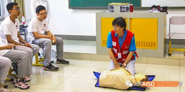 An instructor or teacher demonstrating CPR techniques on a mannequin to students from Beijing No.2 Middle School.