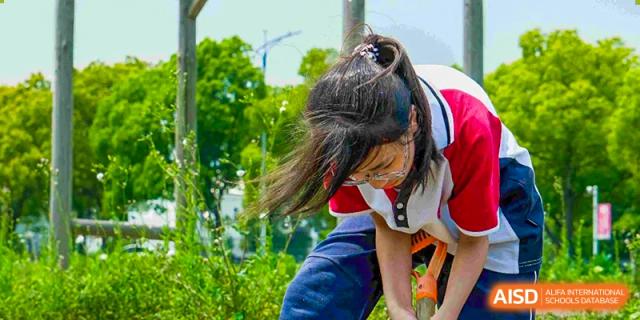 A female student from The International School of Rhodes outdoors with her hair blowing in the wind, possibly during an activity break.