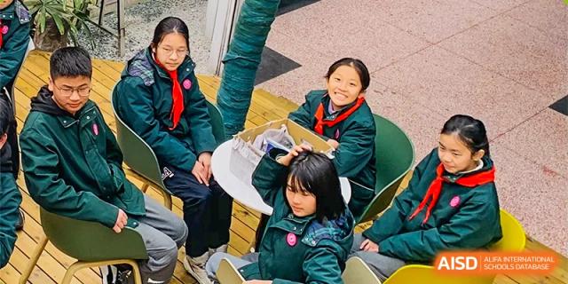 Two young students from The International School of Rhodes smiling while sitting at a table during an outdoor activity.