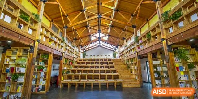 A wide, bright shot of the library or auditorium with wooden benches and high ceilings at The International School of Rhodes.