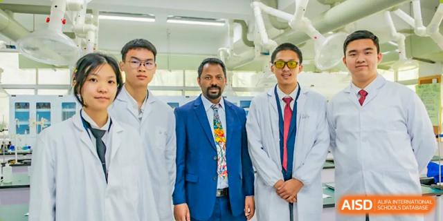 Three male staff members or teachers from The International School of Rhodes posing together, one in a suit, one in a lab coat.