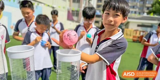 Male students from The International School of Rhodes in uniform engaging in a hands-on science experiment or activity outdoors.
