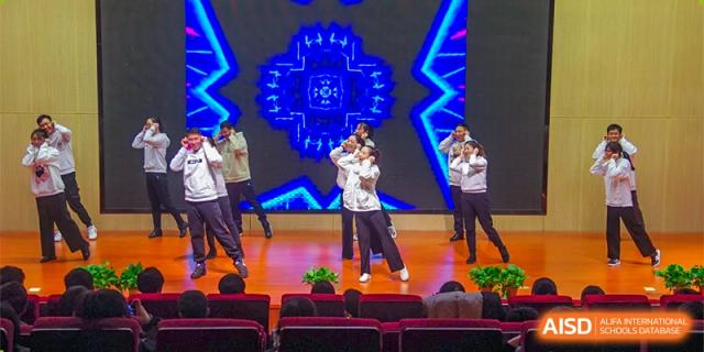 A student from The International School of Rhodes giving an animated performance or dance on a stage.