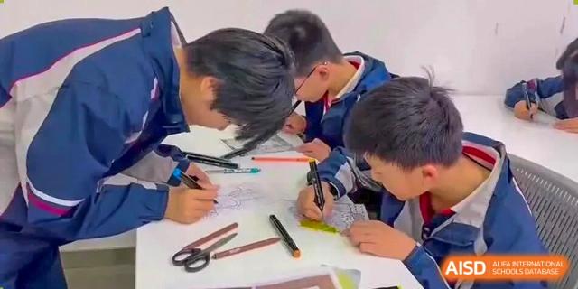 Students from The International School of Rhodes collaborating on a drawing or writing project at a desk.
