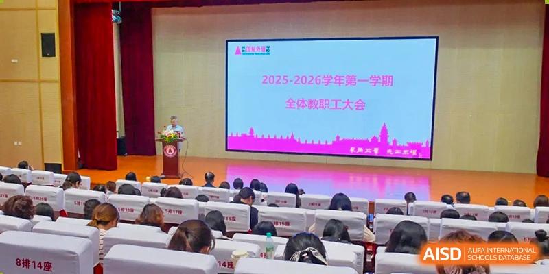 Students from The International School of Rhodes attending a lecture or presentation in an auditorium with a large screen displaying "2025-2026."