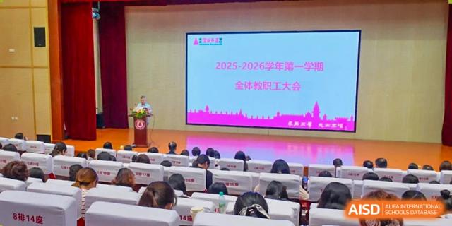 Students from The International School of Rhodes attending a lecture or presentation in an auditorium with a large screen displaying "2025-2026."
