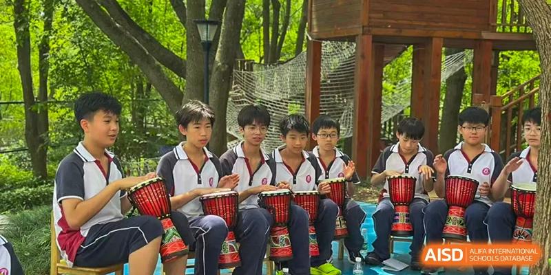 Male students from The International School of Rhodes playing African drums (djembe) outdoors.