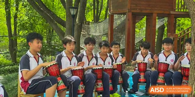 Male students from The International School of Rhodes playing African drums (djembe) outdoors.