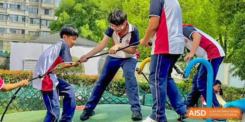 A student from The International School of Rhodes engaging in a hands-on science or engineering activity outdoors, holding two rods.