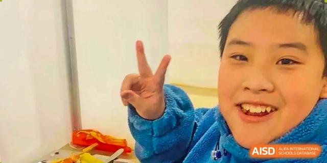 A close-up shot of a young student from The International School of Rhodes making a peace sign gesture.