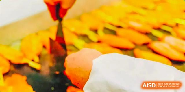 This photo is partially obscured on the left. Assuming it relates to food: A close-up of a pile of bright baked goods or fresh fruit in the school cafeteria at The International School of Rhodes.