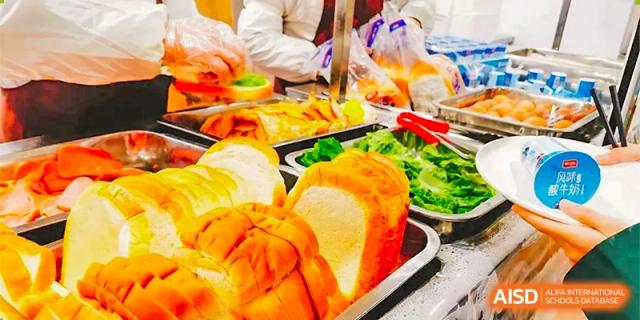 This photo is partially obscured on the right. Assuming it relates to food: A display of fresh fruits, vegetables, and bread rolls ready to be served at The International School of Rhodes.
